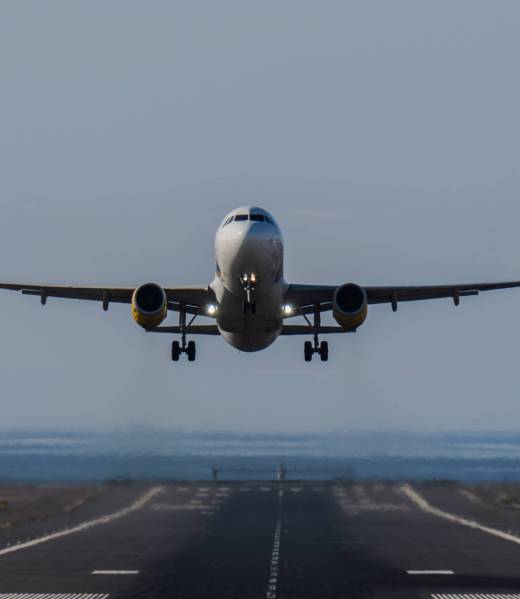Front view of an airplane taking off from the runway with clear sky and ocean in background